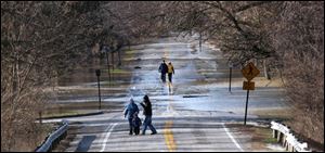 An urge to view disaster is irresistible to walkers checking floods yesterday on River Road at Maumee's Side Cut Metropark. 