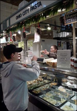 Susan Yacovella, left, manager of the Ohio City Pasta booth at the West Side Market in Cleveland, gives Corbin Wandling, 13, of Akron, a sample of pasta salad.