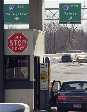A motorist takes a ticket from a dispenser at the Strongsville interchange of the Ohio Turnpike. If workers strike, the turnpike will charge flat rates for cars, trucks, and big rigs.