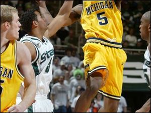 Michigan s Dion Harris makes a pass against Michigan State s Chris Hill. The Wolverines are 12-8, 3-3 Big Ten.