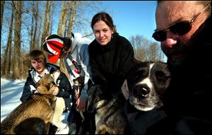 Delta sled-dog racers, from left, Anthony Griffith, Jamie Collier, family friend Stephanie Miler, and Mike Collier, the boys' grandfather, visit their Siberian huskies. The Colliers are one of a half-dozen sled-dog-racing families in the area. 