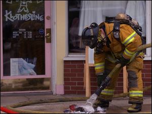 CTY perrysburg fire 1 A firefighter hoses down burnt clothing on a downtown Perrysburg, OH sidewalk where an upstairs apartment caught fire Wednesday, Feb. 16, 2005. The Blade/Lori King