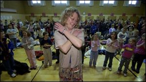 Fifth-grade teacher Pattie Joe Butler leads children in The Macarena dance before school starts.