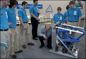 Team Tech Fusion members from Toledo Technology Academy and Rogers High School watch mentor Bruce Vanisacker tweak their robot at Dana Corp.'s Technical Resource Center. The team has worked on its robot for nearly six weeks.