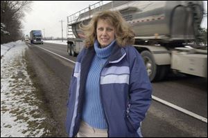 Tractor-trailers provide a backdrop along U.S. 24 for Patricia Rupert of Grand Rapids, who is being honored for her efforts in rescuing an injured woman from behind the wheel of a burning van in November.