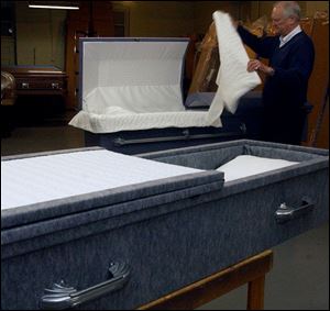 Paul Waltz, of Waltz Casket Co., readies two of his inexpensive caskets used in indigent burials.