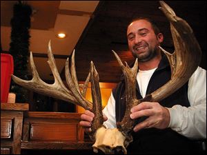 Aaron Davis, a 28-year-old Holland, Mich., bowhunter, shows the 20-point rack of the record buck he took in Hillsdale County.

