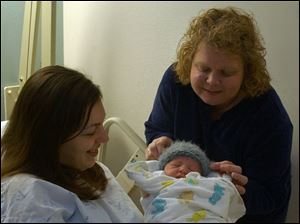 Darlene Michalski, right, puts a knitted cap on Nikolas Guinsler, as the newborn's mother, Christina Guinsler, cuddles him. Knitted caps mark more than one birth