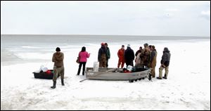 Fishermen rescued Friday from a floe that broke and floated away gather on the shore. Three helicopters assisted the rescue.