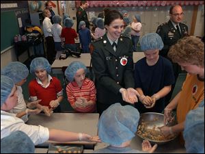 NBR buckeye28p 1 Bowling Green ROTC Cadet Brittany Kull, center, helps Glenwood Elementary School students make Buckeye cookies for a fundraiser for soldiers Monday, Feb. 28, 2005. The Blade/Lori King