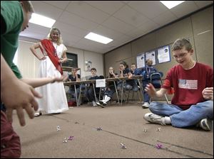 NBR olympic D -- Dustin Carey, left, and Andy Brubaker, right, compete in a game of jacks as social studies teacher Bonnie Urso supervises the competition during the 7-2 Olympics at Springfield Middle School. Seventh grade students were competing Friday, 03/04/05, in such events as chariot races, Olympic tongue twisters, sticky ball, ball in a basket, bubble gum blowing and other events, after having studied ancient Greece. The Blade/Andy Morrison