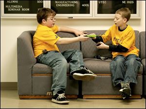 NBR dip05 01 - L-R, Jonathan Boesger and Skylar Sommers, both 11, and from Fayette, share a gameboy as they kill some time inbetween competitions at the Destination Imagination contest at the University of Toledo. The Blade/Allan Detrich