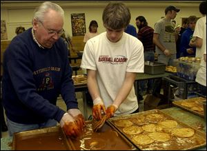 Nelson Yoder, working for his grandson, and Clay Norris, 14, working for his sister Cassie, are on the assembly line.