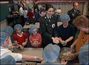 NBR buckeye28p 1 Bowling Green ROTC Cadet Brittany Kull, center, helps Glenwood Elementary School students make Buckeye cookies for a fundraiser for soldiers Monday, Feb. 28, 2005. The Blade/Lori King