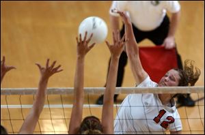 Bedford s Lexi Leonhard spikes the ball against two L Anse Creuse players for one of her 14 kills.
