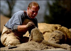 Artist Roger Powell works on one of his sand sculptures, larger-than-life Bible scenes he has been making for five years, at Riverside Park in Findlay.