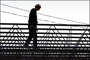 ROV loftywalk 01 - A construction worker balances as he carries some metal across some rafters of a new building being built at the Dave White complex at the corner of Alexis and Monroe Streets.. The Blade/Allan Detrich