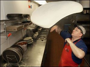 Findlay's Brian Edler lofts and twirls pizza dough as it is stretched to meet the demand of a waiting customer in Defiance.