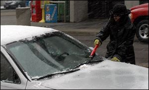 With snow continuing to come down, Jaye Hayes of Toledo cleans the white stuff off her car in downtown Toledo.
