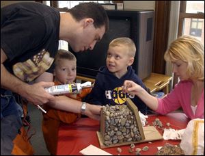 NBR  Wauseon, Ohio.  spring19p   Wauseon Public Library.  l-r  Ken and Vandee Strohschein(adults)  help their boys Dylan 5, and Tyler 4, decorate their birdhouse with stones. Dad is putting on caulk to place the stones.   Diane Hires  3/19/05