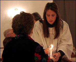 Beth Myers, of Perrysburg, lights the candle of a worshipper before the start of the Tenebrae Service at St. Timothy's Episcopal Church in Perrysburg.