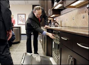Gov. Bob Taft checks out a built-in dishwasher in a display kitchen at the Whirlpool plant in Findlay, where he also talked about his tax reform plan during a roundtable discussion.