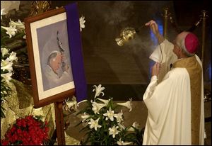 Auxiliary Bishop Robert Donnelly blesses a portrait of Pope John Paul II at a Mass at Rosary Cathedral in Toledo yesterday.