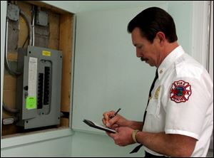 Ron Whipple inspects an electrical box in a Samaria building.