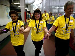 CTY relay 08p    Cancer survivors, Teresa Rossi, left, swings her hands with Jan Bain, center, and Bobbie Conour, right, during the first lap of American Cancers Society Relay for Life at Owens Community College Friday evening 4/8/05  in the gym at the Student Health and Activities Center.   The Blade/Madalyn Ruggiero