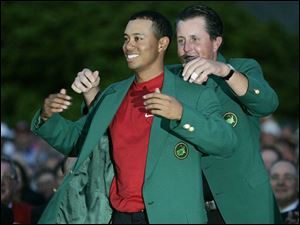 Last year's champion, Phil Mickelson, puts the fourth green jacket on Tiger Woods. Mickelson shot 74 yesterday.