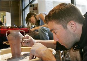 ROV   Raymond Nagley, 22, front, and Shannon Bauerschmidt, 22, back, both studio arts majors at the University of Toledo, demonstrate the art of ceramic making during a 