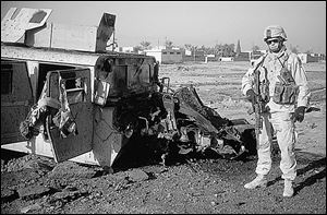Sgt. Chris Adams stands beside the Humvee Sgt. Tommy Brasington, Jr., was riding in when it was hit by a roadside bomb.
