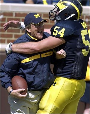 Michigan coach Lloyd Carr is congratulated by offensive lineman Mark Bihl after catching a touchdown pass on the last play of spring practice yesterday afternoon at Michigan Stadium.