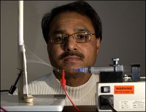 Abdul-Majeed Azad, of UT, checks the progress as a polymer ceramic mixture in a syringe becomes a nanofiber. 