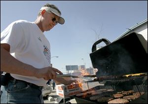 HIS GRILL FRIEND: Dave Costic grills up some juicy burgers for hungry tailgaters near the ball field.