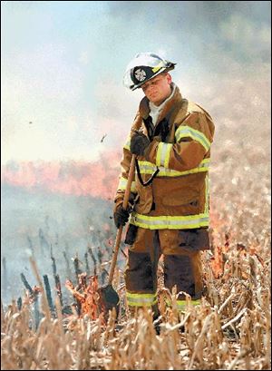 Smoke from a field fire south of Haskins swirls around firefighter Steve Shaner of Washington Township.