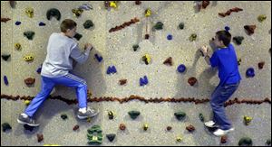 Collin Wingert, left, and Andrew Nasta race across the climbing wall in the gym at Dorr Elementary School.