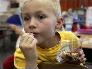 Drew Weber, 7, tries some of the edible landfill while listening to an ecology lesson from BGSU students.