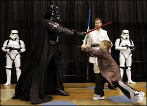 Anthony Campbell, 7, of New Albany, Ind., duels with Darth Vader as Simon Needham of London, as a Jedi master, observes. 