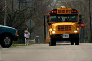 A student keeps an eye on a moving truck after exiting a school bus on Curtice EW Road in Curtice, Ohio, while the bus driver signals the driver of the truck to stop.