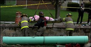 CTY accident26p 1 .jpg  Toledo firefighters lift a construction worker out of 20' hole after a sewer tile the crew was installing broke loose from a crane and hit the worker in the head on Beverly Drive in South Toledo, OH 04/26/2005 The Blade/Lisa Dutton