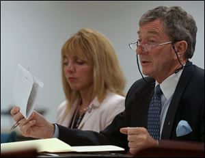 Sheri Caldwell, director of human resources, listens as Toledo Zoo board member Tony Shelbourn holds up a draft copy of a survey the board wants to distribute to employees.