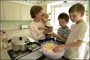 Sue Gilgen of Findlay makes popcorn the old-fashioned way - on the stove - for her children, Patrick, 1, Andrew, 4, and Tommy, 5.