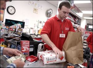 A.J. Reitz bags cartons of cigarettes for a customer at the Barney s Convenience Mart at Detroit
Avenue and Alexis Road. A higher cigarette tax could mean lower sales for Barney s.

