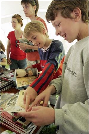 NBR claire21p Nathan Hart, 10, left, and Hunter Elmore, 11, right, enjoy looking at some books that were for sale at Claire's Day at the Maumee branch library on Saturday, 5/21/05. The Blade/Dave Zapotosky
