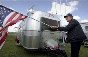 Jack Glouner of Naples, Fla., prepares to raise Old Glory after parking his Airstream at the Sandusky County Fairgrounds.