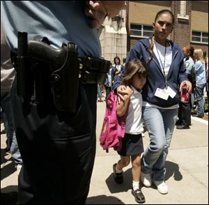 Parents escort  their children  from Riverside School Wednesday after reports of a gun being found in the building. 