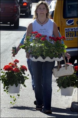 Deb Chirco of Temperance carries geraniums to her car at the Toledo Farmers Market as Susie Gutierrez of Toledo follows behind. Lucas County ranks first in Ohio's 88 counties in floriculture, a $2.5 billion industry nationally. Flower Day, held every Memorial Day Weekend, is an opportunity for gardeners to meet the people who grow the flowers they plant. Hanging baskets are always a popular item.