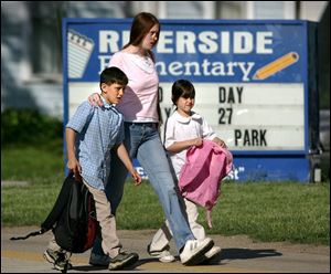 Laura Charles cautiously escorts her children, Anthony, 8, and Tayler, 6, to Riverside Elementary on Thursday, one day after a man carrying two guns was spotted in the building.