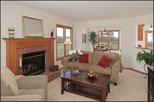 The large family room has a gas fireplace with a red brick surround and raised hearth framed in oak.  Natural woods frame the large windows.